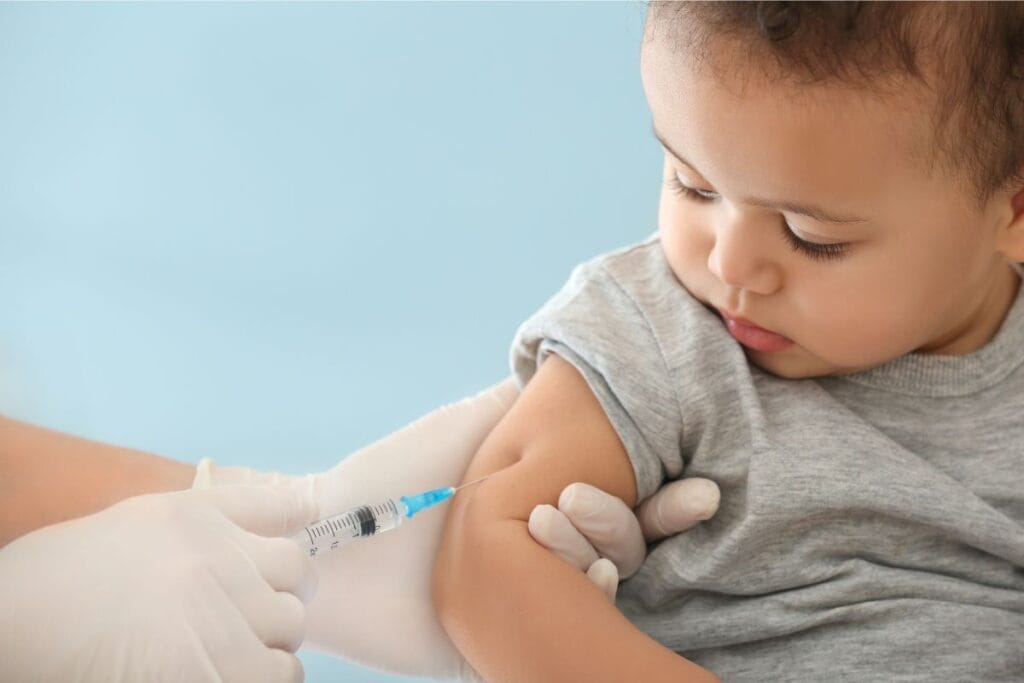 A young child receives a vaccination in their upper arm from a healthcare professional wearing white gloves, highlighting the importance of vaccination in Melbourne, FL.